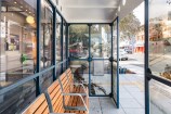Bus shelter in the middle of an urban street with archival images on it and brown benches inside.