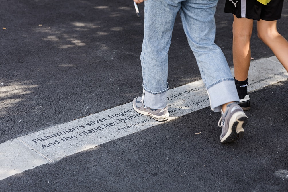 Quotes etched into the pavement with two people walking over the top of them.