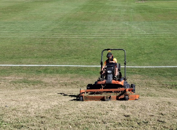 Man wearing high vis on a mower on a field.