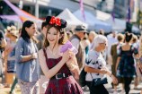 A woman in a checkered dress wearing mickey mouse ears. 