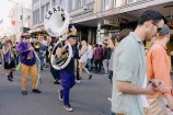 A person holding a large instrument walking down the street.