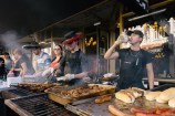 People cooking outdoors infront of a restaurant.