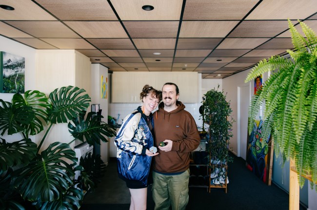 Two people standing side by side in the middle of an apartment.