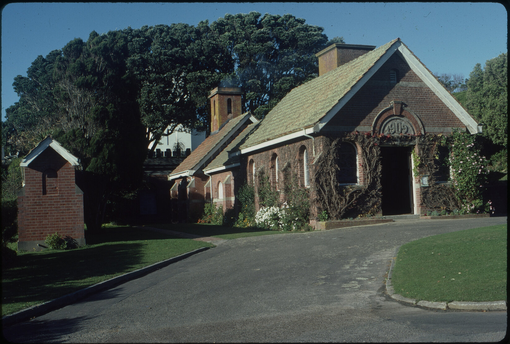 Brick building with trees surrounding it, with a driveway leading up to the crematorium.