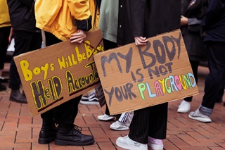 Two people holding signs as part of the sexual violence prevention 'Let Us Live' rally.