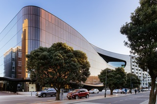 Large glass building with trees reflected in the windows. 