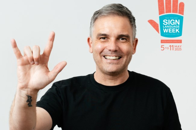 A person wearing a black tshirt and signing.
