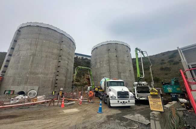 Construction around two large digestor tanks with a truck parked infront of it.