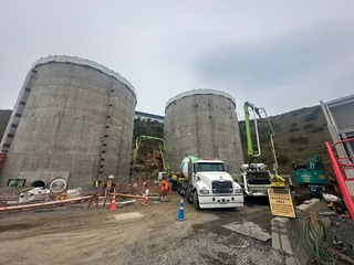 Construction around two large digestor tanks with a truck parked infront of it.