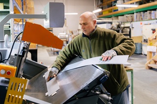 A person moving cardboard onto a machine.