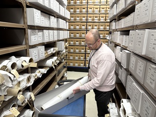 Person placing an item in a box with shelves surrounding them.