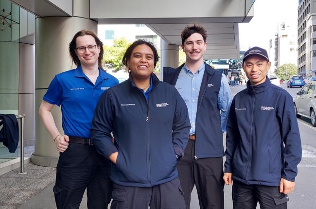 Group of four people standing on the street wearing blue uniform.