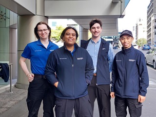 Group of four people standing on the street wearing blue uniform.