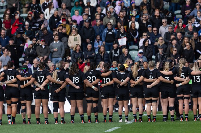 Black Ferns face the crowd from the field with arms linked ahead of match.