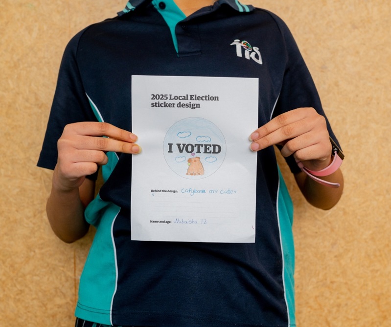 A kid holding their drawing