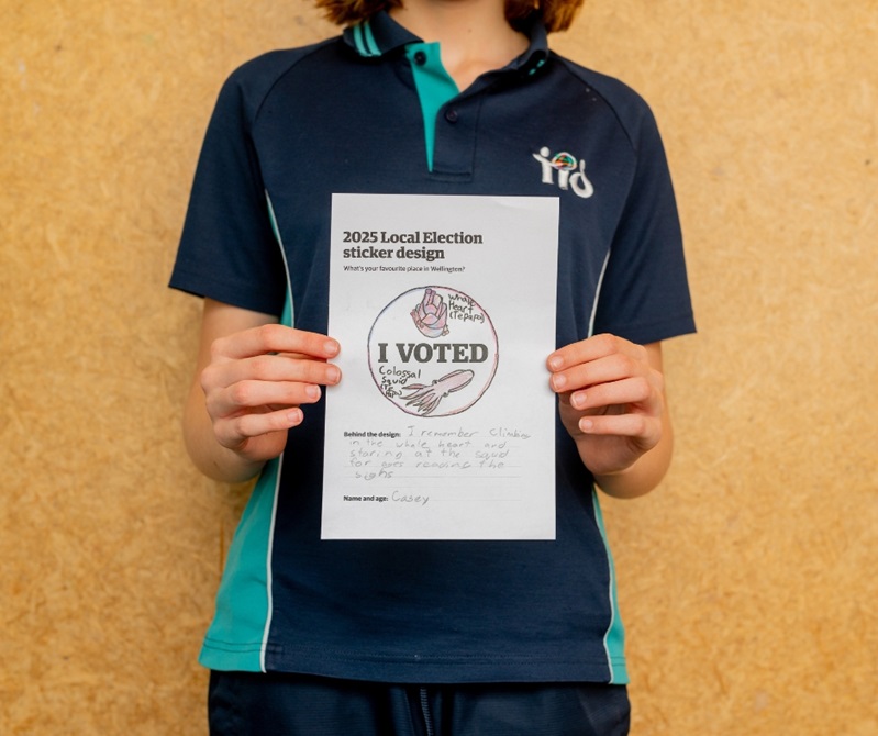 A kid holding their drawing