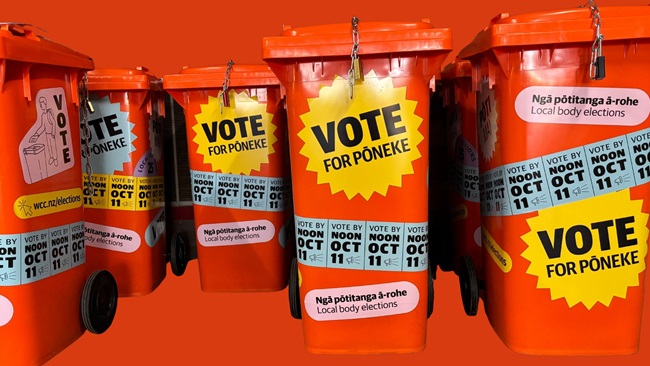 Orange voting bins with stickers plastered all over with details about voting