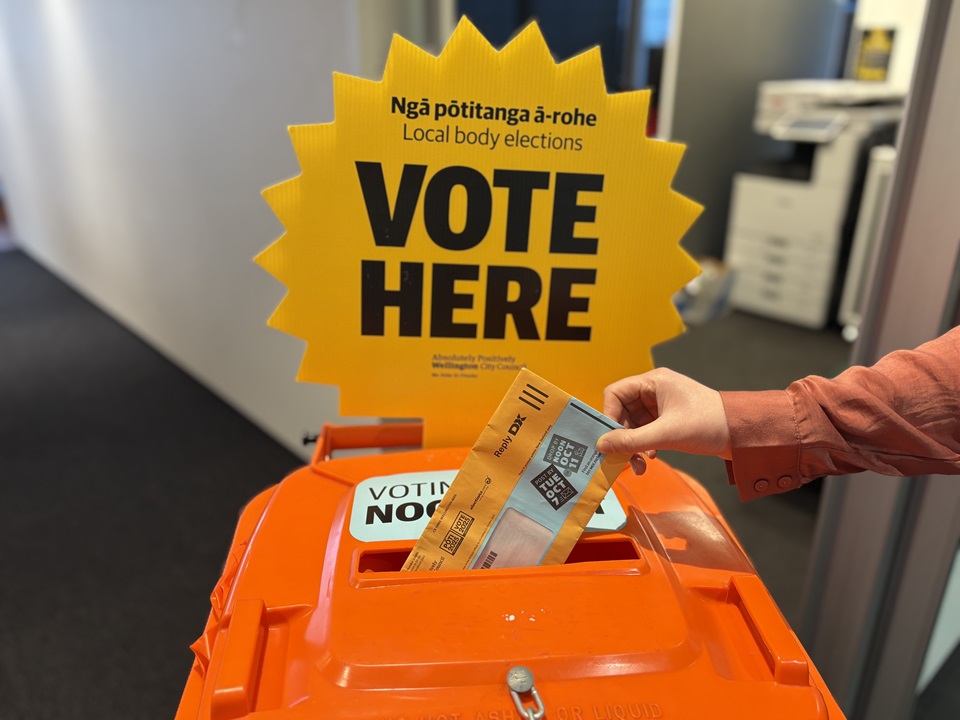 Voting papers being dropped into orange voting bin.