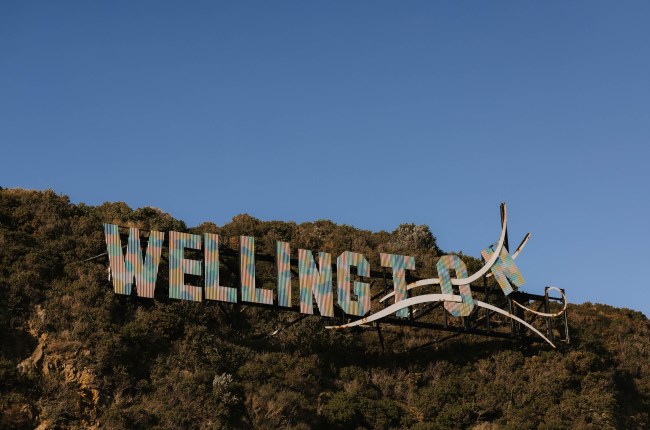 A hillside with giant letters that spell out WELLINGTON, set against a clear blue sky.