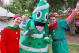 People dressed as Christmas elves pose with a person dressed as a Christmas tree.