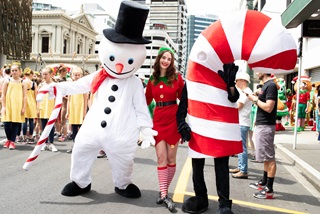 Performers dressed as a snowman, an elf, and a Candy cane pose for a photo at A very Welly Christmas.