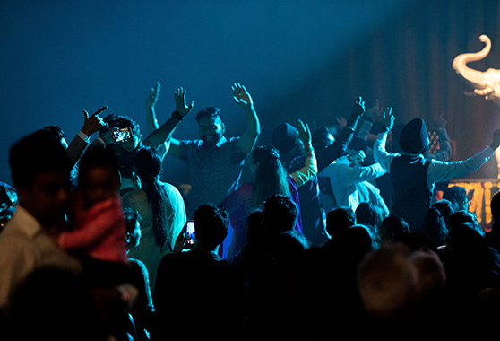 People in a darkened crowd dancing to music.