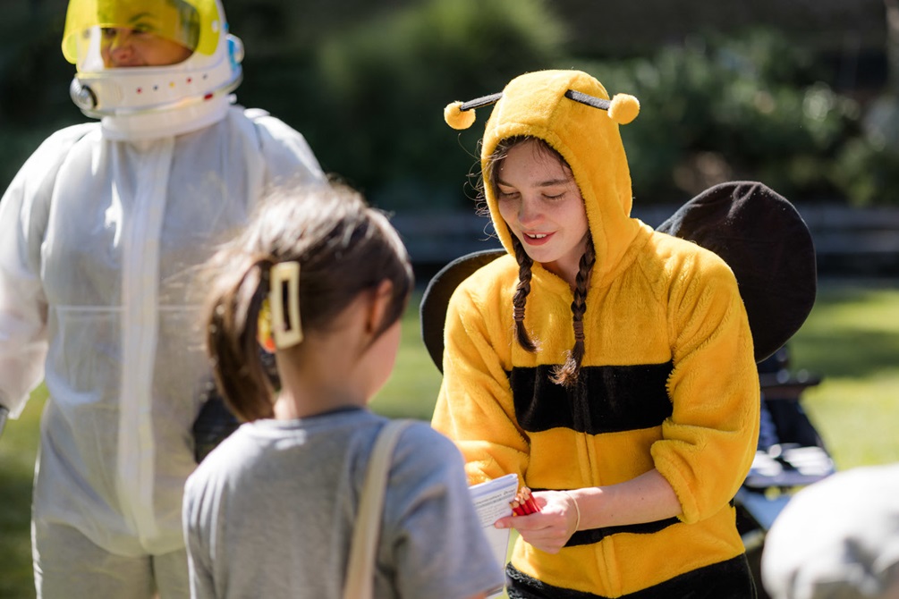 A girl in a bee costume entertains a child.