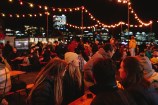A crowd of people seated at picnic tables outdoors at night.