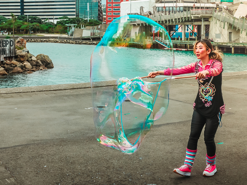 A performer creating a huge bubble on the waterfront.