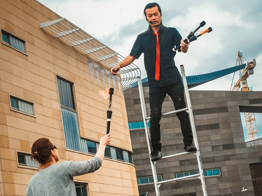 A performer balancing on a ladder and juggling.