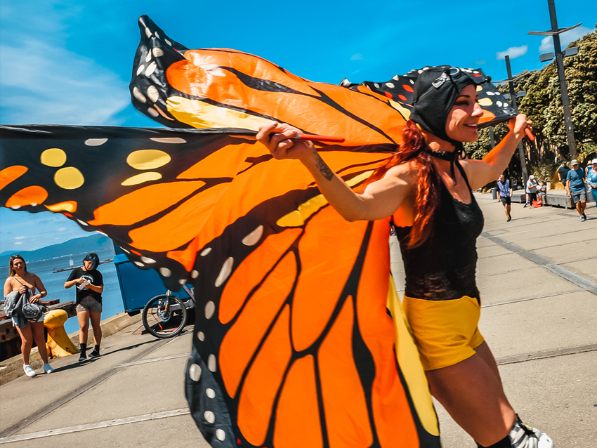 A performer with a giant butterfly cape flying out behind them.