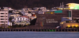‘Kia Kaha Te Reo Māori’ is projected on the side of the Te Papa building as viewed from across the waterfront.