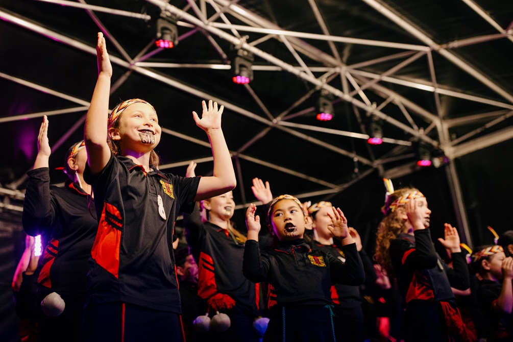 A group of children in matching uniforms performing kapa haka.