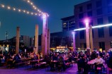 Crowds of people sit at dining tables in Odlins Plaza. A variety of food trucks are visible in the background.