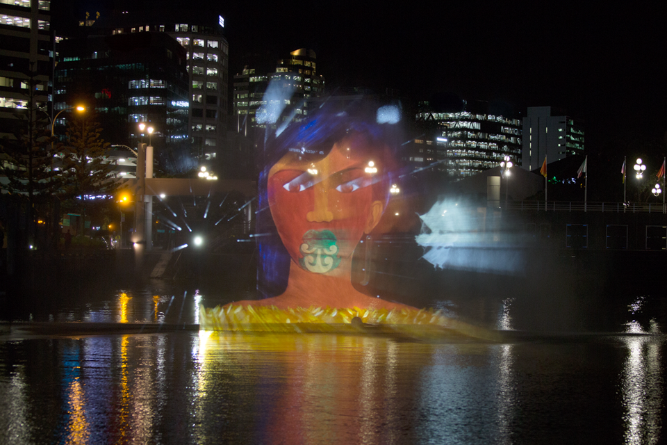 A projection of a māori woman over the water as part of the Mana Moana Pōneke art installation.