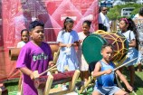 A group of children learning to play a variety of pacific drums.