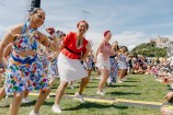 A group of performers dancing in the park in front of a seated crowd.
