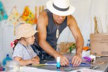 An older man helps a young child build a kite.