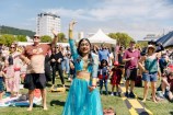A crowd of people dancing to music. At the front of an image is a young woman in traditional Indian dress.