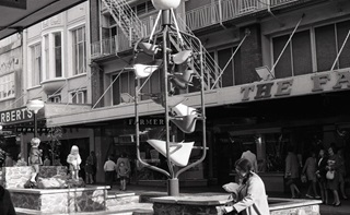 Image of bucket fountain and woman sitting in foreground