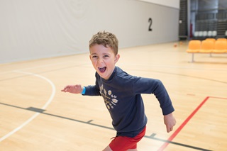 Happy child running on a court at Ākau Tangi Sports Centre.