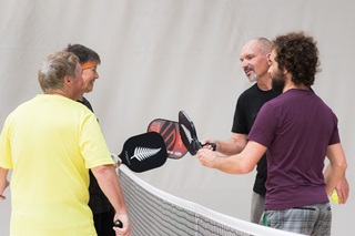 Four adults standing around a net while playing pickleball at Ākau Tangi Sports Centre.