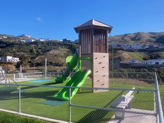 A play area with a tower reached by climbing wall. Two slides lead down from the turret at the top.