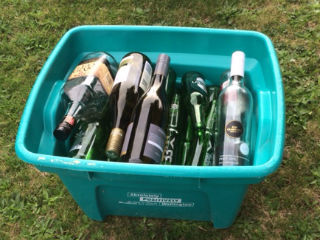 Green recycling crate filled with glass bottles.