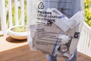 Official suburban recycling bag containing paper and cardboard and plastic.