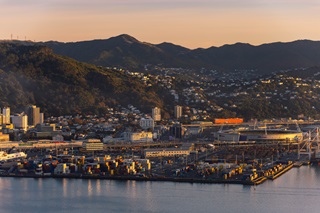 View of Wellington city port with the sky stadium, motorway and houses in the background on the hills and the harbour in the foreground.