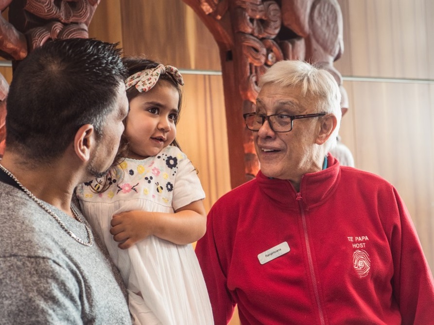A Te Papa host talking to a young girl and her father.