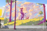 Large mural of a person on a bike with a dog next to them.
