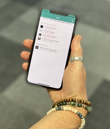 Image of hand holding phone with FixIt app on screen