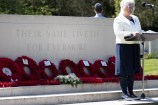 A woman speaks from a lectern in front of the Anzac memorial.